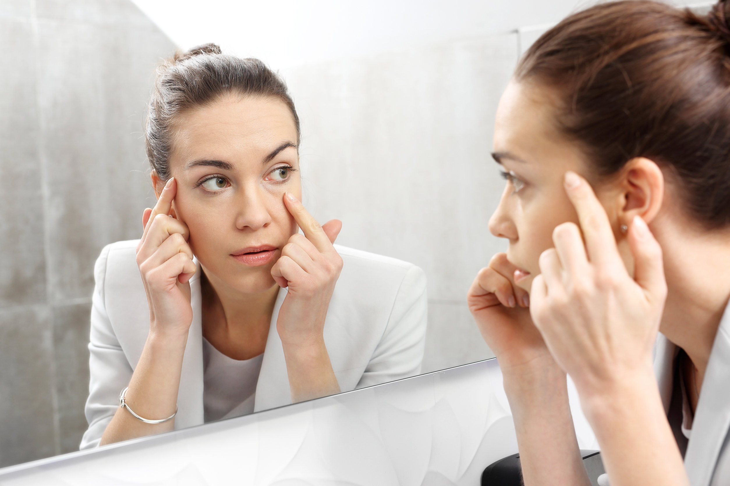 Reflection in the mirror. Woman looks in the mirror noticing the first wrinkles